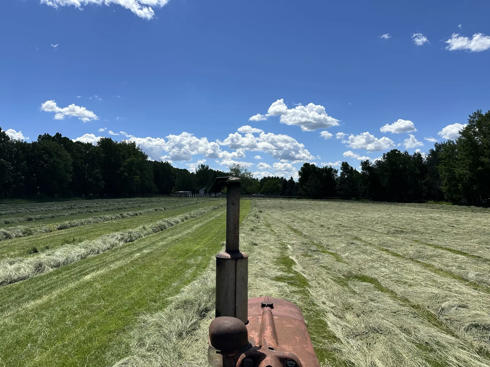 Baling hay with the tractor under a blue summer sky